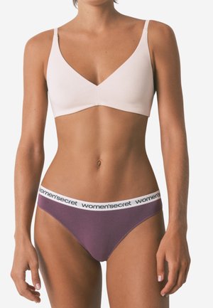 Lichtroze draadloze beha met een gladde textuur en V-hals ontwerp. Gecombineerd met paarse slipjes met een witte merkband.