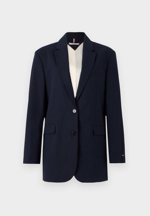 Blazer navy avec deux boutons, revers crantés et poches à rabat à l'avant. Doté d'une doublure intérieure contrastante en crème. Coupe ajustée et texture lisse.