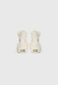 Vita hög-top canvas sneakers med gummisula. Funktioner inkluderar snörning, en rund logotyp på sidan och varumärkesnamn på hälen.