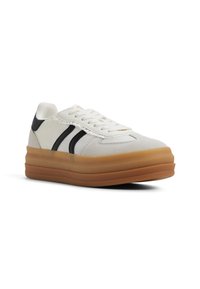 Sneaker bianca in tela con strisce nere, parte superiore testurizzata e suola in gomma traslucida spessa. Presenta una punta arrotondata e chiusura con lacci.