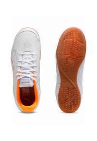 Białe trampki Puma z pomarańczowymi akcentami, posiadające perforowaną syntetyczną cholewkę, zapięcie na sznurowadła oraz teksturowaną gumową podeszwę.