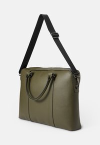 Bolso de cuero sintético verde oliva con dos asas superiores y una correa negra desmontable. Presenta un diseño minimalista y detalles de costura sutiles.