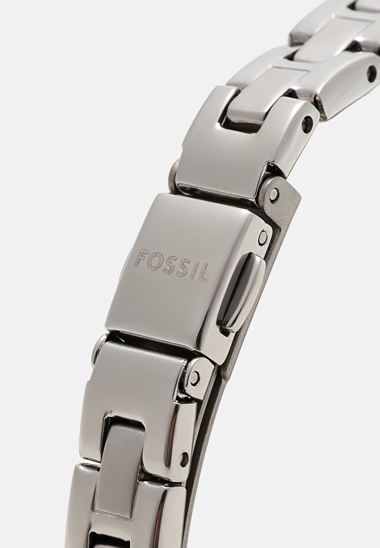 Stainless steel watch with a polished finish, featuring a link bracelet design and a clasp; "FOSSIL" engraved on the metal.