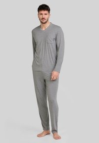 Pijamas de algodón gris de manga larga con escote en V, bolsillo frontal y cinturilla elástica. Textura suave, diseño ajustado y tela transpirable.