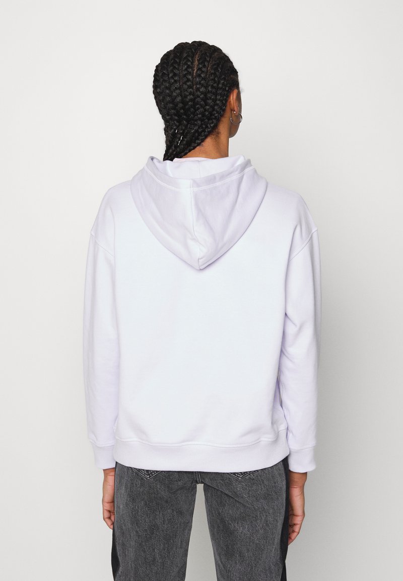 Felpa bianca con cappuccio grande, silhouette oversize, polsini e orlo ribattuti. Tessuto liscio con dettagli di cucitura minimi.