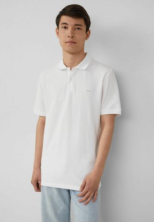 Weißes Poloshirt mit einem Knopfleistenkragen, kurzen Ärmeln und einem dezenten Logo. Getragen mit hellblauen Jeans aus Denim. Einfaches und sauberes Design.