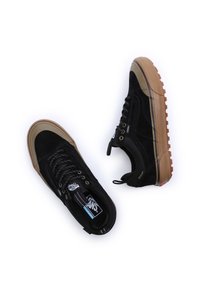 Paired de baskets montantes Vans noires avec semelles en caoutchouc marron et lacets, présentées sur fond blanc.