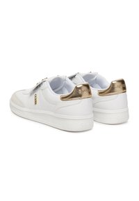 Zapatillas blancas con acentos en beige y detalles del talón en dorado metálico. Material de cuero suave, forma de punta redonda y suela de goma texturizada.