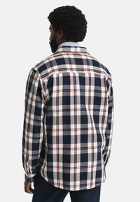 Camisa de cuadros con un patrón en azul marino, blanco y rojo, fabricada en tejido texturizado, con cuello abotonado y mangas largas.