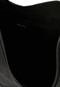 Interior de un bolso de cuero negro con textura suave y cierre de cremallera. En el interior presenta un pequeño bolsillo con cremallera a lo largo del costado. Detalles mínimos.