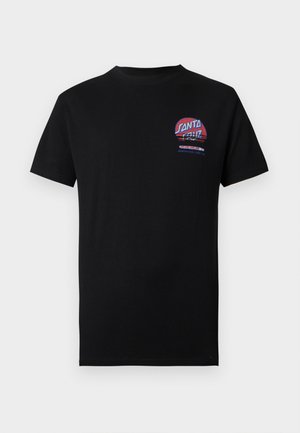 Osoba ubrana w czarny T-shirt z grafiką monitora komputerowego i klawiatury otoczonych czerwonymi płomieniami oraz tekstem "Santa Cruz" na ekranie.