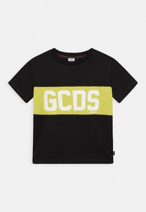 Camiseta de algodón negra con una franja horizontal amarilla que lleva "GCDS" en letras blancas en negrita y "JUNIOR" impreso debajo. Mangas cortas.