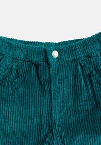 Tealfärgade kordfläskbyxor med vertikal ribbad textur, ett elastiskt midjeband med rynkdetalj och en enda metalknapparstängning framtill.