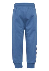 Blå joggingsbyxor med en mjuk textur, elastisk midja och ribbade muddar. Har ett vitt diagonalt randmönster ner längs ett ben.