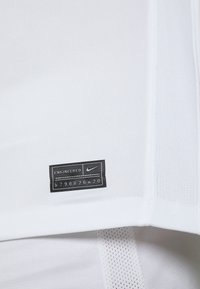 White athletic garment featuring a textured upper panel, smooth lower section, and a black tag labeled "ENGINEERED" with Nike logo.