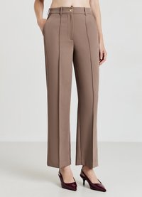 Pantalon marron ajusté à taille haute avec deux poches avant, un pli cousu et une fermeture à bouton doré. Tissu lisse, coupe droite.