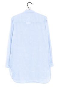 Jasnoniebieska koszula z długim rękawem, z klasycznym kołnierzykiem, z przodu zapinana na guziki i z bocznymi rozcięciami. Miękka tekstura i proste wykończenie, prezentowana na wieszaku.