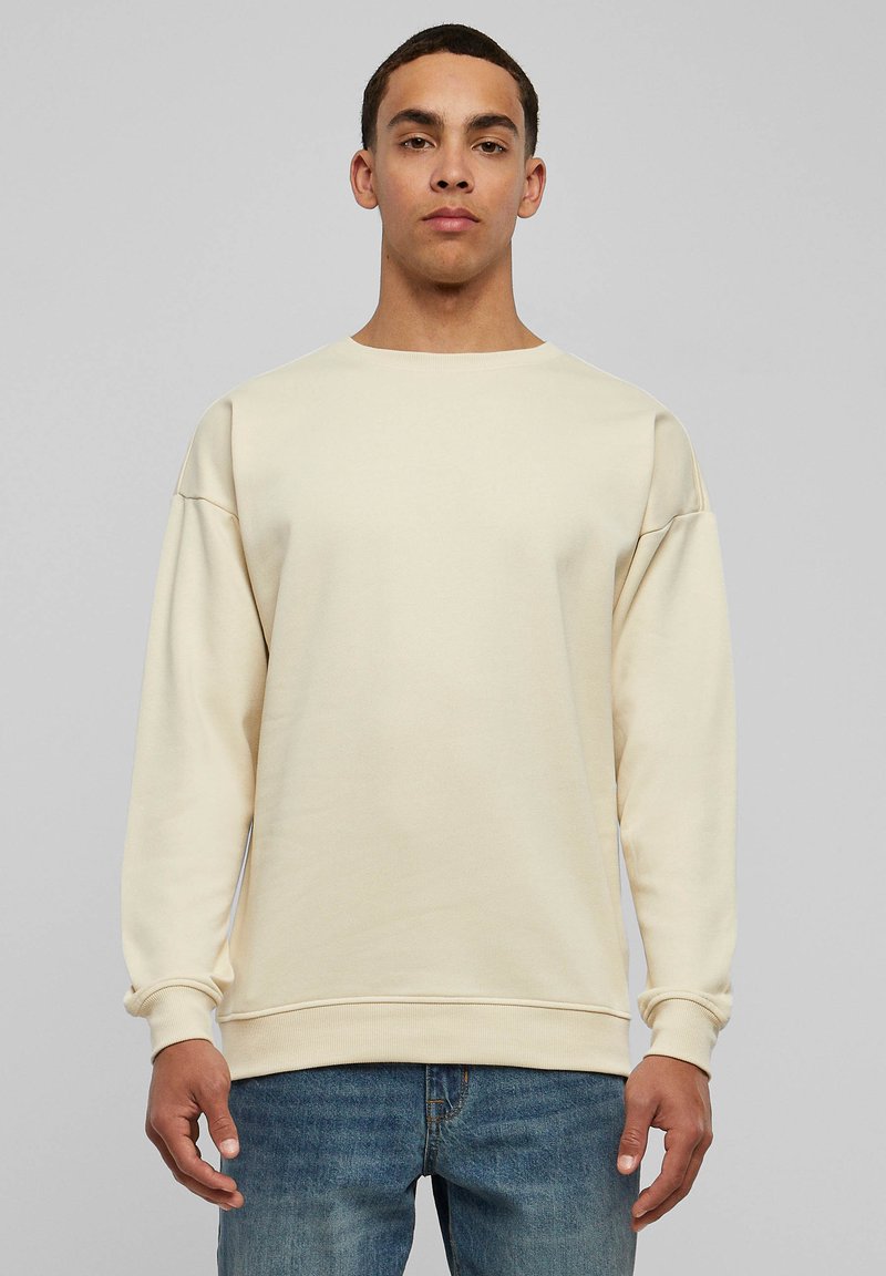 Beige sweatshirt with a round neck, relaxed fit, and long sleeves. Made of soft fabric with ribbed cuffs and waistband. No patterns or accents.