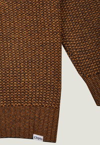  gestrickter Pullover in dunklen Braun- und Orangetönen, mit einem strukturierten Zickzackmuster. Rippbündchen und Saum mit einem kleinen Etikett, das "Clepto" zeigt.
