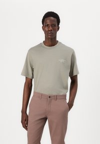 Camiseta de algodón verde claro con cuello redondo y mangas cortas. Combinada con pantalones ajustados de color rosa claro. Diseño simple, sin patrones ni logotipos.