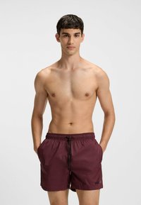 Bordowe kąpielówki wykonane z lekkiego materiału, z elastycznym pasem z sznurkiem i bocznymi kieszeniami. Akcenty z logo na dole.