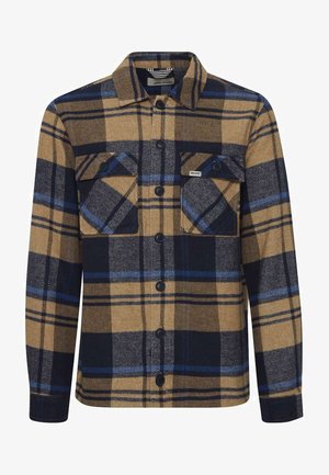 Camicia di flanella a quadri nei toni del marrone, blu navy e azzurro. Presenta due tasche sul petto, chiusura con bottoni e maniche lunghe con polsini abbottonati.