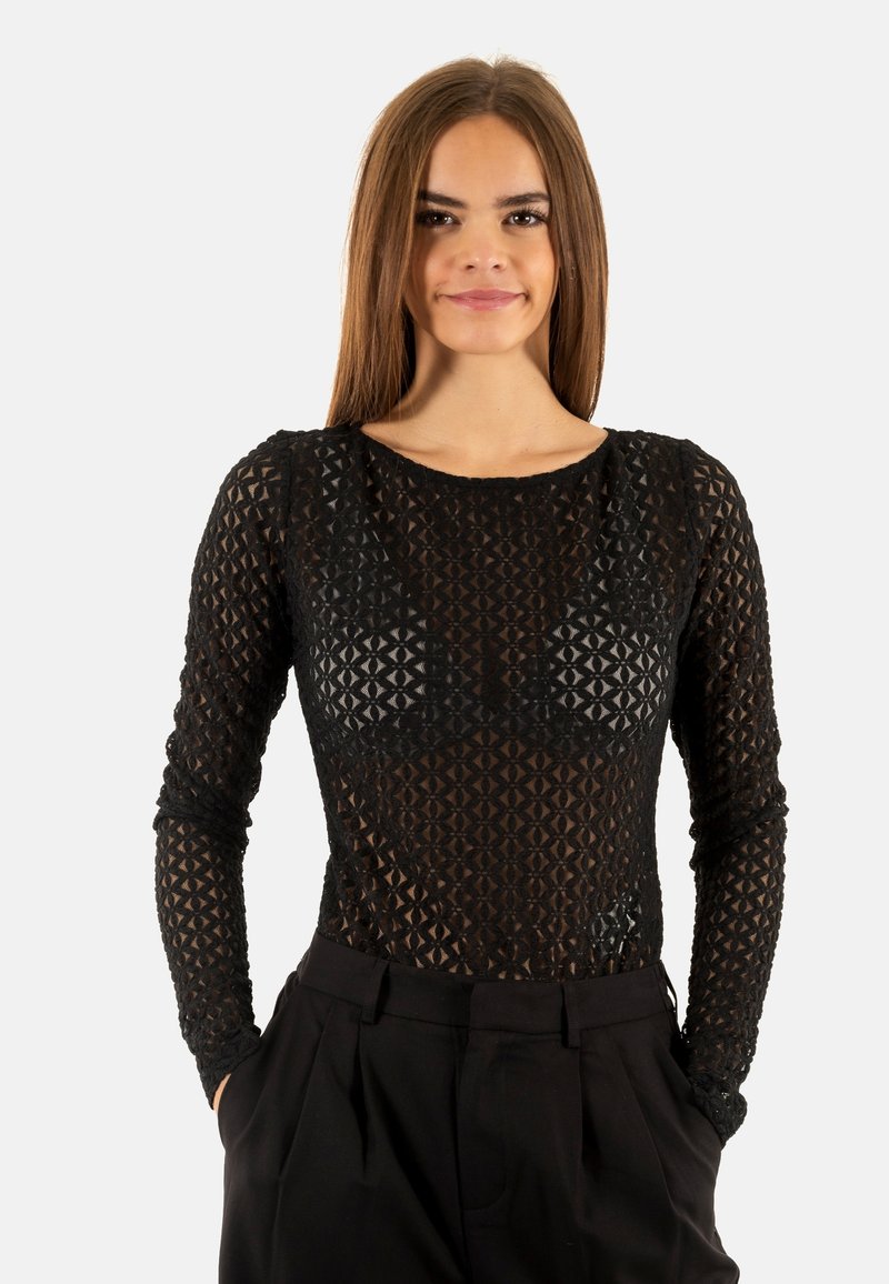 Bodysuit noir à manches longues en tissu transparent et texturé, orné d'un motif géométrique. Associé à un pantalon noir taille haute.