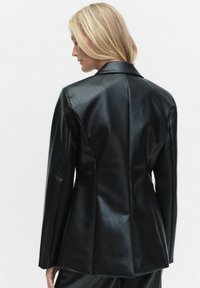 Svart läderblazer med en strukturerad design, skarpa slag, långa ärmar och en skräddarsydd passform med bakseamer för en strömlinjeformad look.