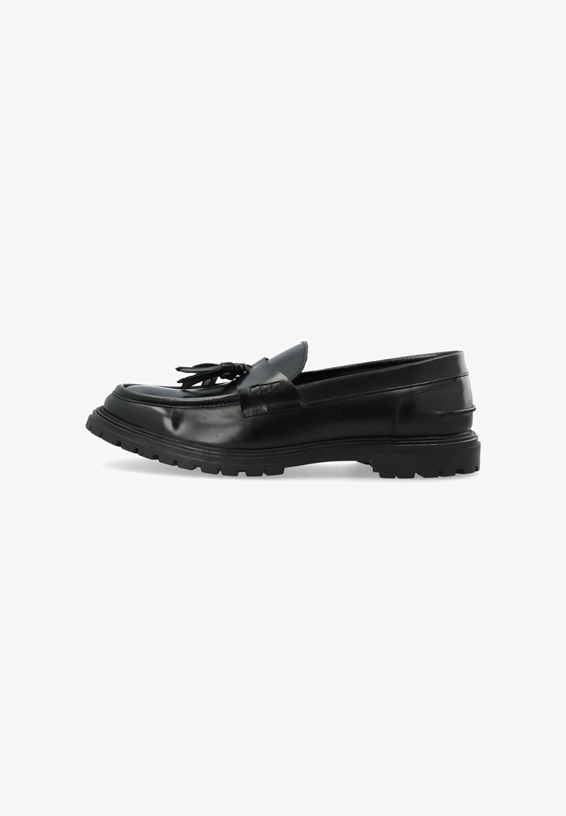 Mocassins en cuir noir avec un bout arrondi, des gland décoratifs et une semelle extérieure robuste. Texture lisse avec des détails de couture minimaux.
