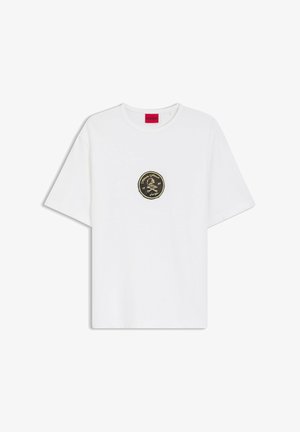 Hvid T-shirt med korte ærmer, rund halsudskæring og lille sort og guldfarvet dødningehoved- og benkryds-badge centreret på brystet.