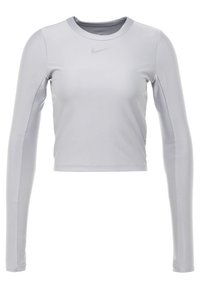 Lichte grijze lange mouwen cropped sportshirt met ronde hals en klein Nike swoosh logo gecentreerd onder de halslijn.