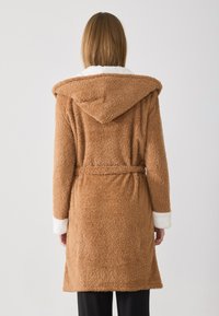 Brown, fluffy bathrobe with a hood. Features white sherpa lining on the collar and cuffs, with a belt at the waist.