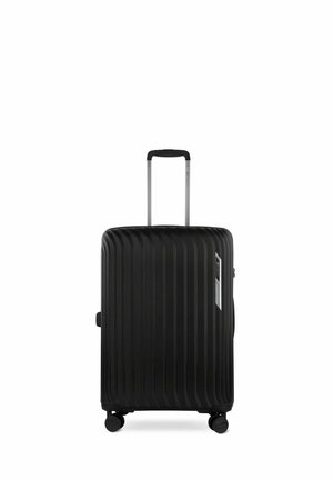 Valise rigide noire avec texture à rainures verticales, poignée rétractable et quatre roulettes pivotantes pour une mobilité optimale. Comprend une poignée latérale et un détail de logo.