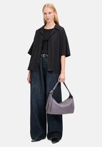 Schwarzes, oversized Hemd, enges schwarzes Top, weit geschnittene, dunkelblaue Jeanshose und graue Ledertasche mit schickem Design und Tragegurt.
