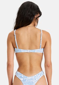 Jasnoniebieski bikini z wzorzystym wzorem, z cienkimi ramiączkami i zapięciem z tyłu. Tekstura wydaje się gładka i elastyczna.