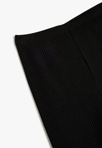 Mustat ribattua leggingsit, joissa on saumaton vyötärö ja pystysuora kuvio, slim fit -mallilla ja yksinkertaisella suunnittelulla monipuolisuutta varten.