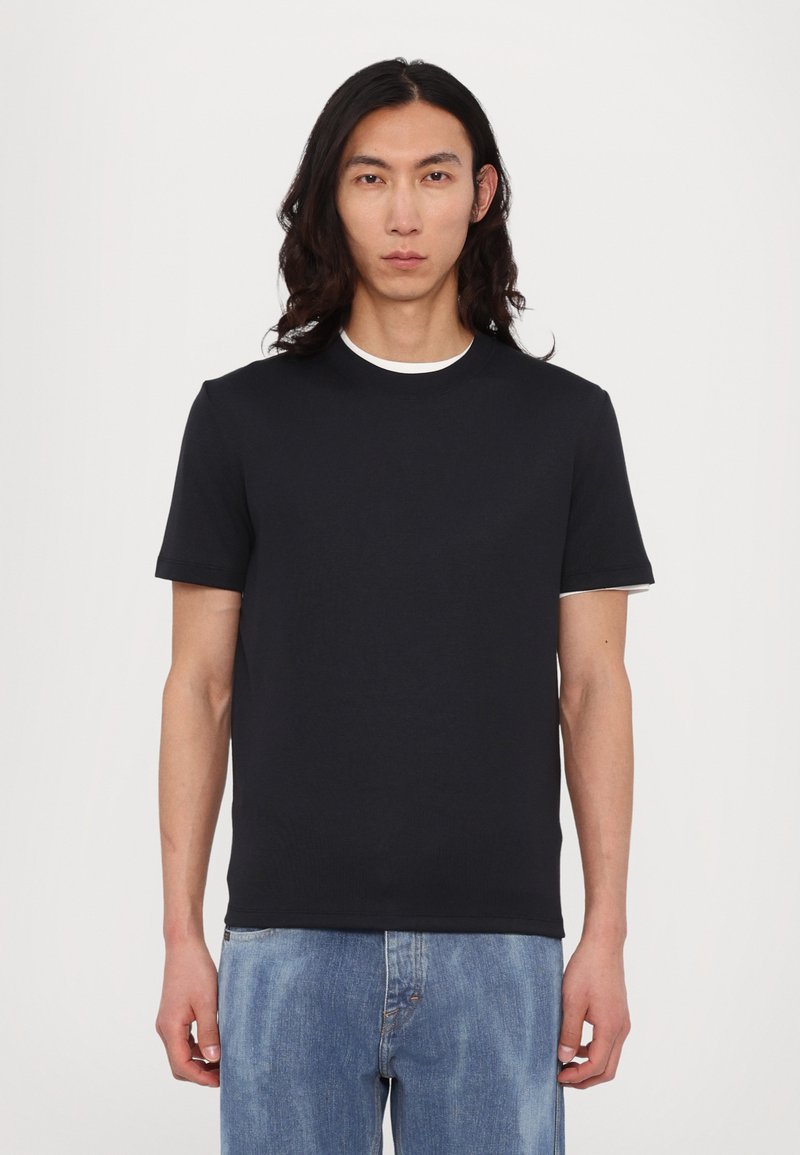 Navy kortermet t-skjorte med rund hals, laget av glatt bomullsstoff, sammen med lyseblå denimjeans.