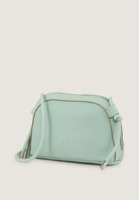 Miętowo-zielona skórzana torebka na ramię z teksturowanym wykończeniem, z zamkiem błyskawicznym, kontrastującymi brązowymi akcentami i cienkim regulowanym paskiem.