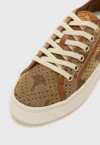 Sneaker marroni con motivo, upper in tessuto a trama, lacci crema, accenti marroni e design della suola arrotondata. Presenta dettagli in hardware dorato.