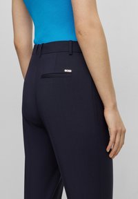 Pantalones marinos con una textura suave, que presentan un bolsillo trasero y un pequeño logo plateado de "BOSS". La cinturilla está diseñada para un ajuste ceñido.