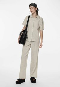 Camicia a righe beige e crema e pantaloni a gamba larga abbinati, realizzati in tessuto leggero. Sandali neri con plateau e una borsa nera con un accento di sciarpa.
