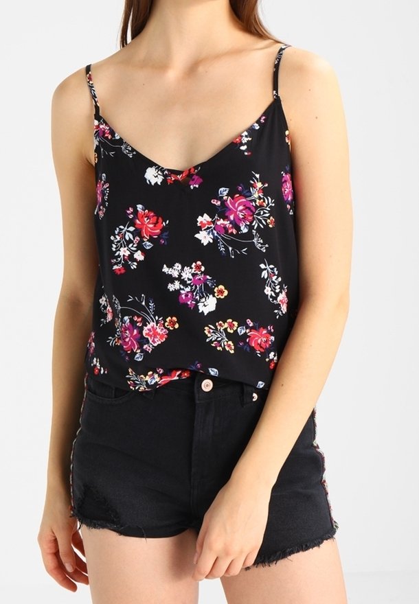Camiseta de tirantes finos de flores negras, con coloridas rosas y pequeñas flores. Combinada con pantalones cortos de mezclilla negros de cintura alta.