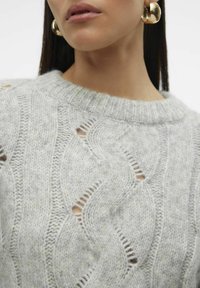 Pullover grigio chiaro lavorato a maglia con collo rotondo a coste, caratterizzato da un motivo ondulato e dettagli in pizzo. Il tessuto sembra morbido e texturizzato.