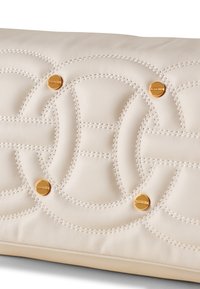 Pochette en cuir crème avec des motifs circulaires matelassés, des accessoires en métal doré et des coutures contrastantes pour une apparence texturée et luxueuse.