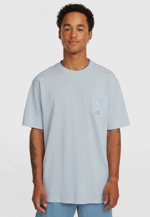 Camiseta de manga corta de color azul claro con un bolsillo en el pecho, confeccionada con tela texturizada y con un pequeño logo en el área del bolsillo. Corte holgado.