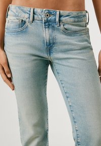 Vaaleansiniset farkut, joissa on slim fit -tyyli, viisi taskua, hienovarainen haalistuminen ja nappikiinnitys vyötäröllä.