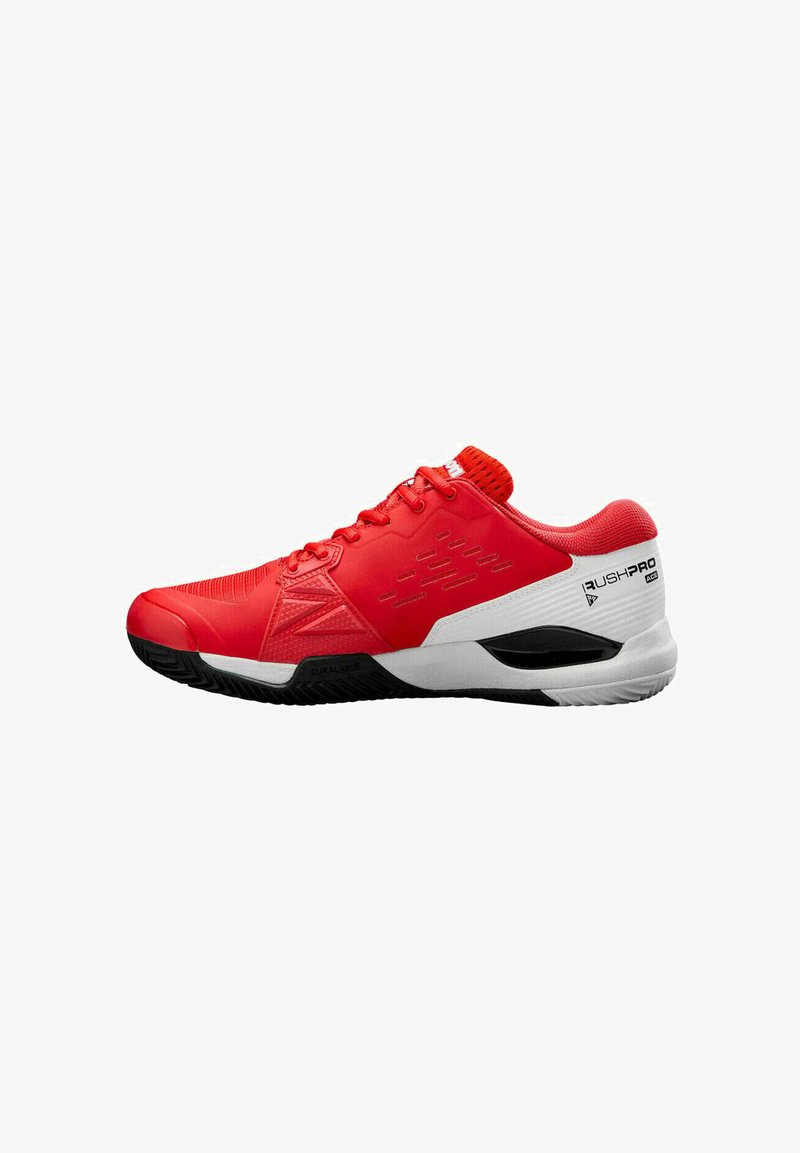 Zapatilla deportiva roja con parte superior de malla texturizada, suela de goma negra, acentos blancos y una marca prominente en el lateral.