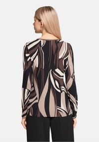 Długopis z długim rękawem z czarnym, beżowym i brązowym abstrakcyjnym wzorem liści. Wykonany z miękkiej tkaniny, z okrągłym dekoltem i luźnym krojem.