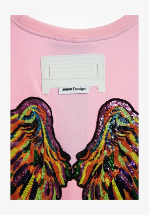 Top de tela rosa con diseños de alas de lentejuelas coloridas en naranja, púrpura y verde, con una etiqueta blanca en el cuello que dice "MWM Design."