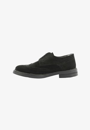 Scarpa nera in suede con lacci, dettagli perforati, punta arrotondata e suola in gomma testurizzata bassa. Gli elementi di design presenti migliorano la traspirabilità.